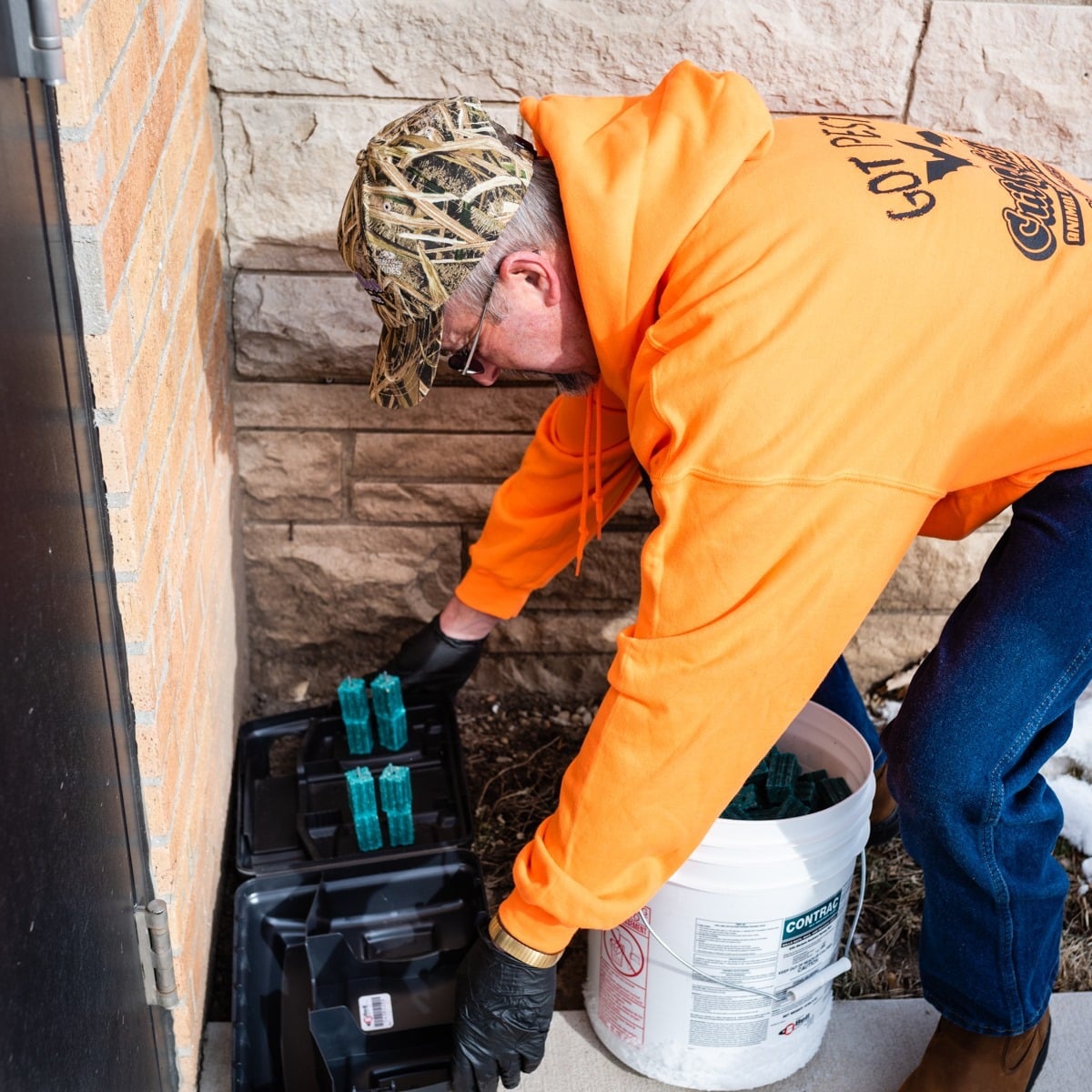Critters Inc. technician placing a rodent station outside a property